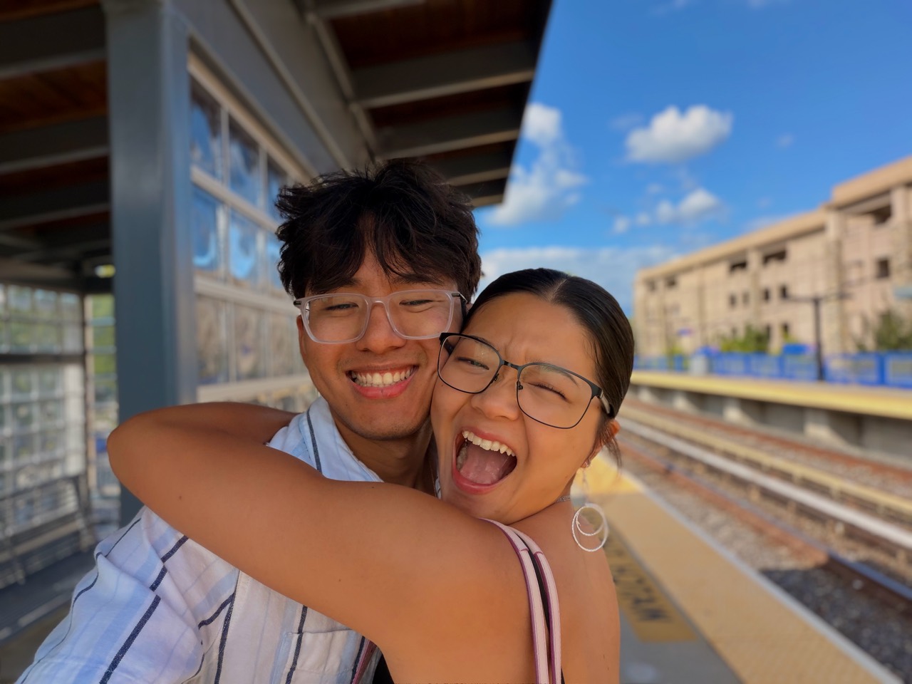 Two friends smiling and embracing on a train platform